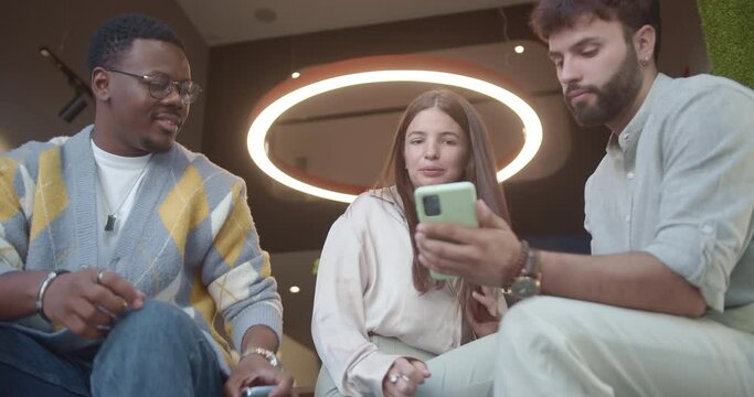 Three multiracial employees sitting on a door jamb working together on a new project, planning step by step for successful work and better profit or efficiency.