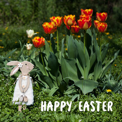 Greeting card with text Happy Easter in English. Decorative Easter bunny against background of beautiful red tulips in spring garden. Nature, outdoor