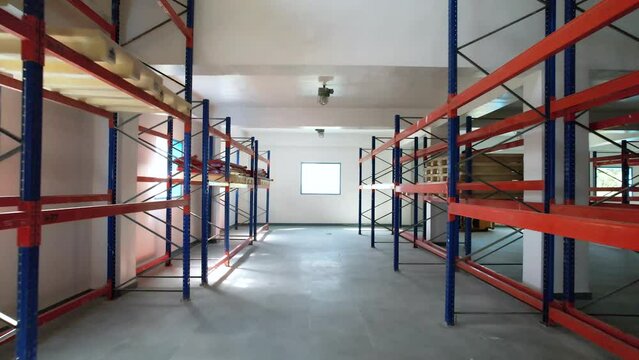 Empty warehouse area with colored racks for storage and epoxy flooring in a pharmaceutical manufacturing factory for active pharma ingredients, speciality chemicals, hazardous chemical	