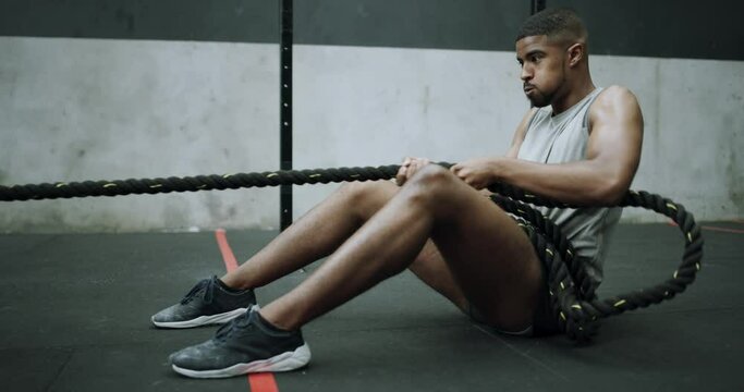 Man, fitness and pulling rope for workout, exercise or training on floor for muscle or strength at gym. Active male person, athlete or bodybuilder in weightlifting, challenge or sled pull at club