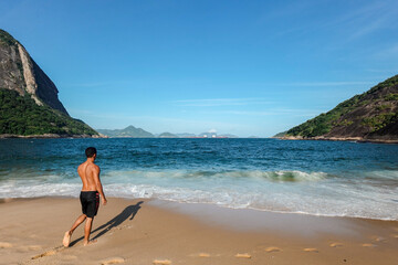 Hombre caminando hacia el mar de la playa Vermelha en Rio de Janeiro en Brasil