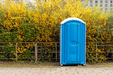 Portable dry toilet located near the bush. Portable dry toilet close-up.