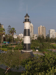 Vertical image of the Miraflores lighthouse in Lima, Peru. Surrounded by vegetation and with the light of the sunset. Photograph taken with a drone.