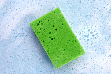 Cleaning sponge in foam of dishwashing liquid. Washing dishes concept