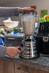 Close-up of a woman activating a blender to prepare a smoothie