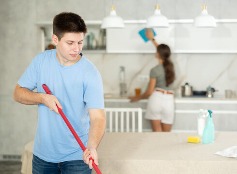 Fototapeta Guy mops floor until it shines during group cleaning in kitchen