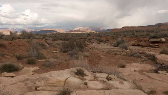 4k time lapse video taken from the viewpoint of a dry ravine on a cloudy spring day in the desert of Southern Utah looking towards the mountains of Zion Nat. Park.