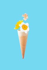 Ice cream cone and natural daffodils on blue background. Minimal creative floral food concept. Copy space.