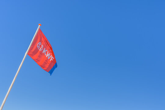 Katwijk, The Netherlands - June 11, 2022: The flag of the Queen Wilhelmina Fund (KWF) for the Dutch fight against cancer waves on a flagpole against a clear blue sky