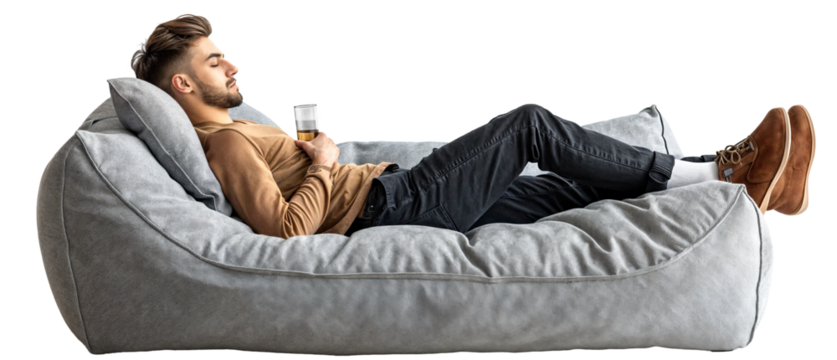 handsome young man lying relaxed on a a cozy, modern, grey sofa and holding a drink in his hand, isolated on a transparent background