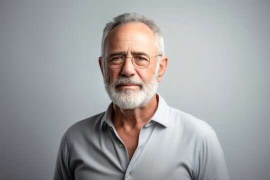 Portrait of a handsome senior man in glasses on grey background.