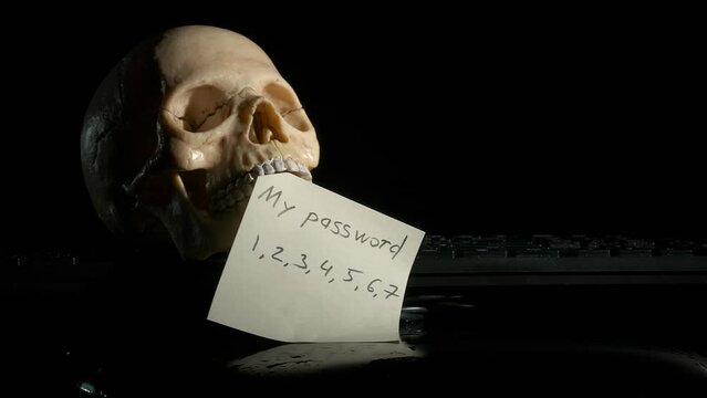 Sticky note with password by keyboard. A view of sticky note with written easy password in the skull mouth on keyboard against black background. A concept of hack the website.