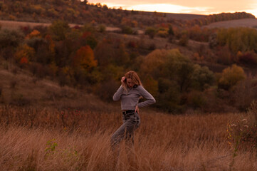 Naklejka na ściany i meble Young attractive blonde woman standing on the hill at sunset 