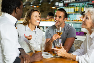 Diverse people happy talking and drinking beer at a bar table