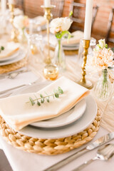 A close-up of a dinner plates with napkins, silverware, candles, and florals.