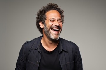 Portrait of a happy latin man laughing over grey background.
