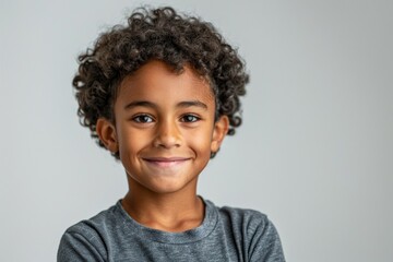 A young boy with curly hair is smiling and looking at the camera