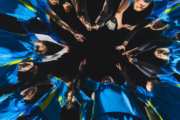 low angle view of football player girls standing in a circle and holding hands up before a match. High quality photo - obrazy, fototapety, plakaty