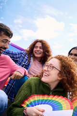 Vertical. Group diverse young people smiling in gay pride festival day holding rainbows fans....