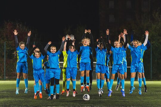 full shot of young girls jumping in the air for the team photo, school football club. High quality photo