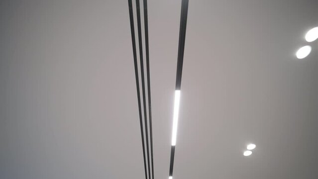 Ceiling view showcasing the contrast of sleek, modern LED strips and traditional spotlights in a contemporary interior