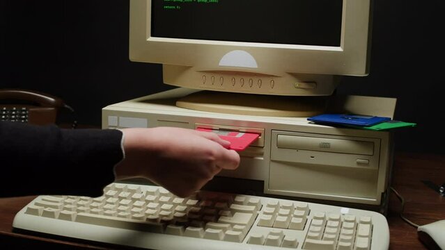 Using diskette FDD for old computer close-up. Hand inserting and ejecting Floppy Disk into vintage PC. Music recorder, playing retro computer games. 