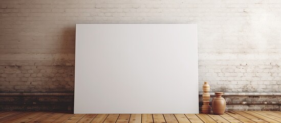 A blank white poster placed on a rustic wooden floor in front of a textured brick wall - obrazy, fototapety, plakaty