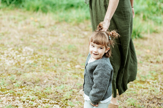 Joyful child holding hands with adult in nature