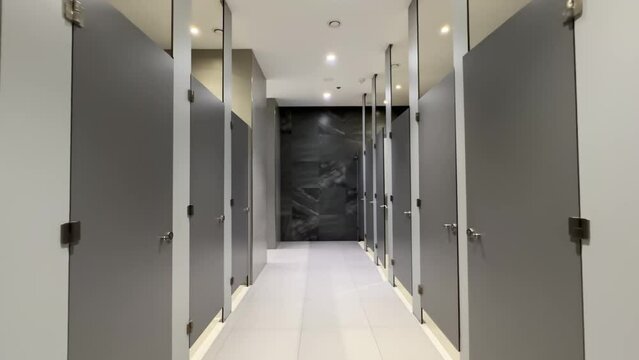 Contemporary Public Restroom with Rows of Closed Stall Cubicles and Partitions Lining Both Sides