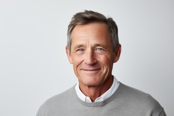Handsome middle aged man in grey sweater smiling at camera.