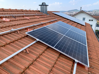 Solar panels on the roof of a house with red tiles