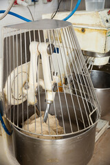 Baker preparing the dough for bread in a dough mixer