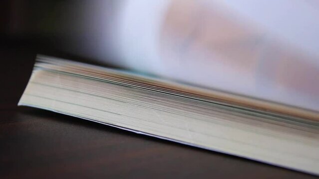 Hand finger flipping school textbook pages on table surface 1