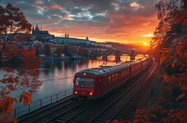Tuinposter A picturesque scene with a red train crossing a bridge over a river during a vibrant sunset, with foliage framing the view © Dacha AI