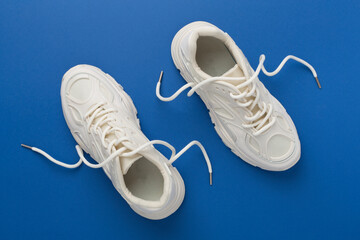 White woman trendy sneakers on color background, top view