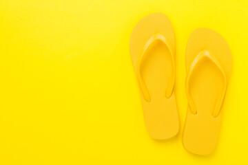 Bright yellow flip-flops on color background, top view. Summer concept