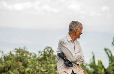 retrato de hombre mayor al aire libre en el campo cos sus brazos cruzados mirando a un costado