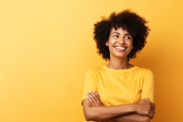 Obraz na płótnie Canvas Portrait of a smiling afro american woman with crossed arms looking away over yellow background