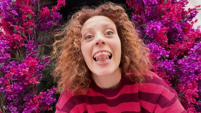 Joyful redhead woman laughing near vibrant purple flowers