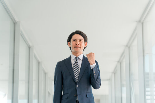 ガッツポーズするスーツ姿の若いアジア人男性ビジネスマン（保険業・金融業・保険営業・アドバイザー）
