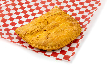 A Jamaican or Caribbean meat patty on a red and white checked paper