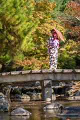 a woman stands on a bridge with an umbrella over her head.