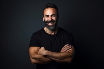 Handsome bearded man in black t-shirt smiling and looking at camera. - obrazy, fototapety, plakaty