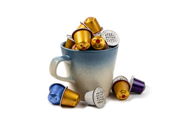 A colorful pile of used coffee maker pods in a coffee cup isolated on white