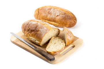 A whole loaf of artisanal crusty bread with slice cut off on a wooden cutting board  and another loaf in the background isolated on white