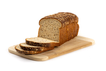 A sliced loaf of whole grocery store wheat bread on a wooden cutting board isolated on white
