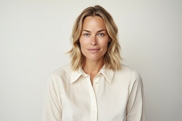 Portrait of a beautiful blond woman in a white shirt on a gray background