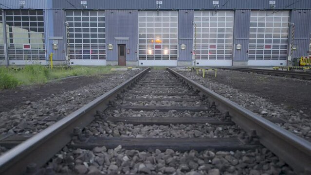 Twilight at a rail depot, tracks leading into a train maintenance building