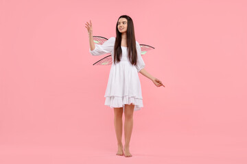 Beautiful girl in fairy costume with wings on pink background