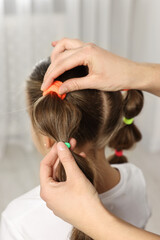 Naklejka premium Professional stylist braiding girl's hair indoors, closeup